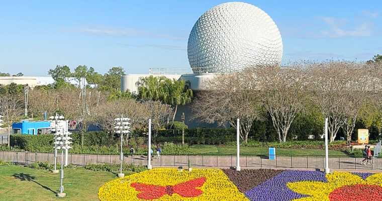 Spaceship Earth with colorful flowers in the foreground at EPCOT in Walt Disney World.